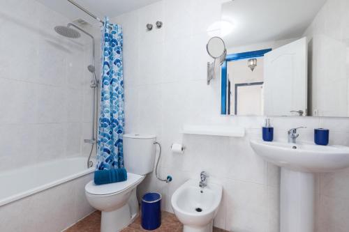 a white bathroom with a toilet and a sink at Home2Book Casa La Pepita 2 in Caleta De Fuste