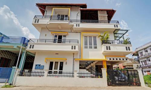 a tall white house with a balcony at Treebo Trend Alaka Rester Homestay in Madikeri