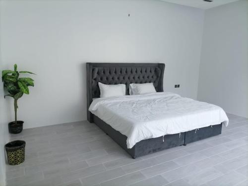 a bedroom with a large bed with white sheets and a plant at شاليه اللويمي in Al Hofuf