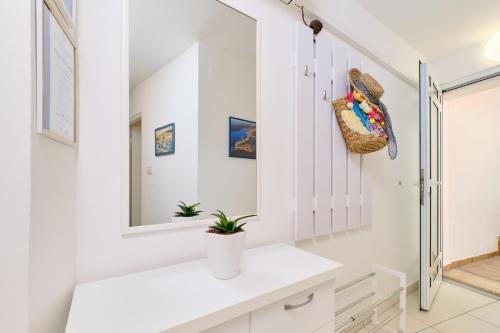 Baño blanco con lavabo y espejo en Apartments Antares en Mali Lošinj