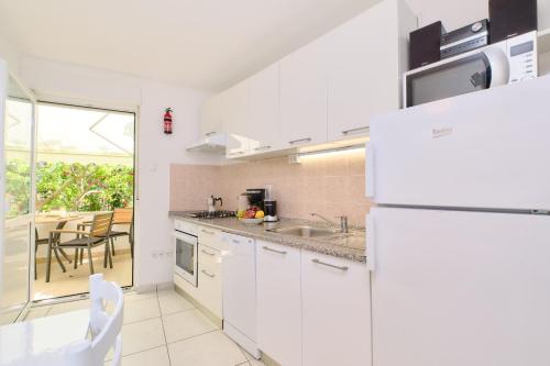 a kitchen with a white refrigerator and a table and chairs at Apartments Antares in Mali Lošinj