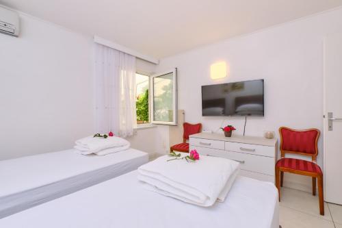 Habitación blanca con 2 camas y TV. en Apartments Antares en Mali Lošinj