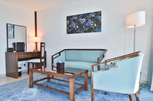 a living room with a blue couch and a desk at Coral Tower Hotel by Hansa in Amman