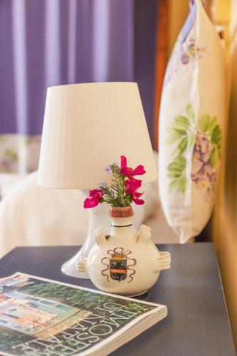 a table with a lamp and a vase with flowers in it at Agriturismo Montevecchio Isolani in Monte San Pietro