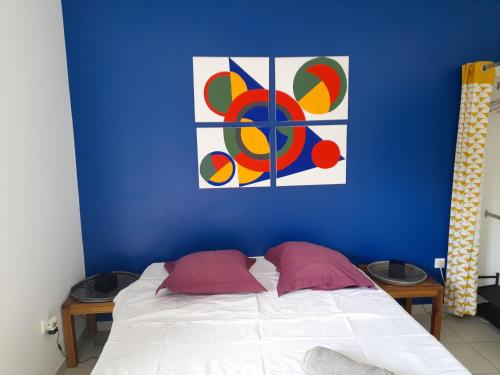 1 dormitorio azul con 1 cama con una pintura en la pared en Chambre avec salle de bain, WC et terrasse, en Étang-Salé