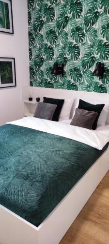 a bedroom with a bed with a green and white comforter at Nowoczesny apartament z widokiem na park in Rzeszów