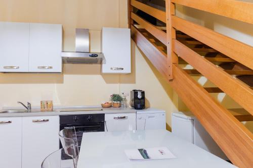 a kitchen with white cabinets and a spiral staircase at Agriturismo Montevecchio Isolani in Monte San Pietro