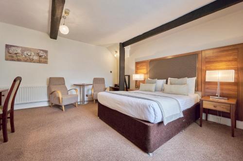 a hotel room with a bed and a table and chairs at The Old Ginn House Inn in Great Clifton