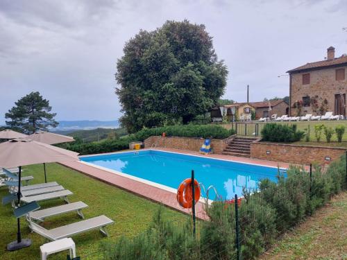 einen Pool mit Stühlen und einem Sonnenschirm in der Unterkunft Casa Vacanze "L'Aione" in Gambassi Terme