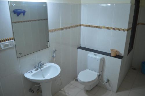 a white bathroom with a toilet and a sink at Hotel City Palace in Brahmapur