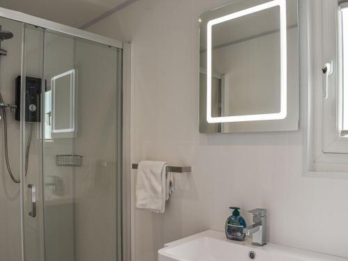 a bathroom with a shower and a sink and a mirror at Uk39216 - Swn Y Mor in Holyhead