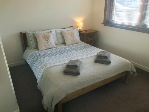 a bedroom with a bed with two towels on it at Cluaran Cottage in Tain