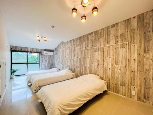 Duas camas num quarto com painéis de madeira em UMIBE IseShima em Shima