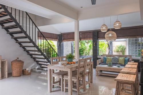 Un comedor con escalera y mesa y sillas. en Villa Karma Legian, en Legian