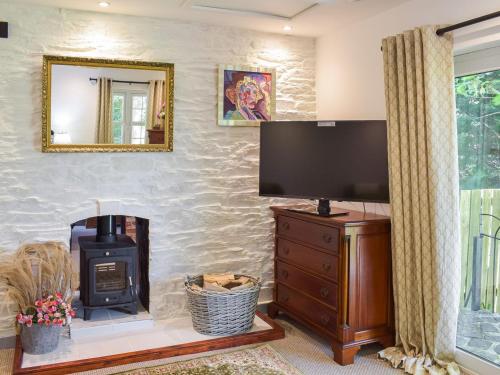 a living room with a fireplace and a flat screen tv at The Coach House in Cove