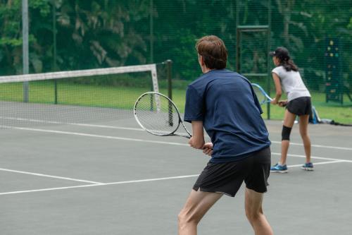 two people playing tennis on a tennis court at San Lameer Villa 3212 - 4 Bedroom Superior - 8 pax - San Lameer Rental Agency in Southbroom