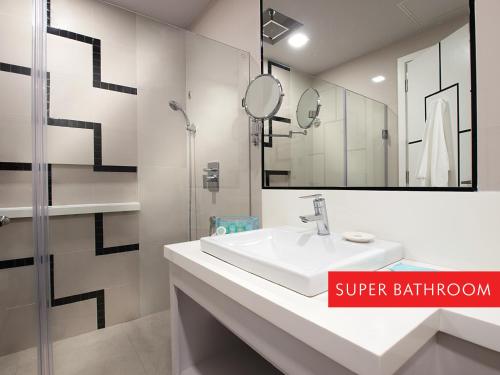 a white bathroom with a sink and a shower at Summit Hotel Magnolia in Manila