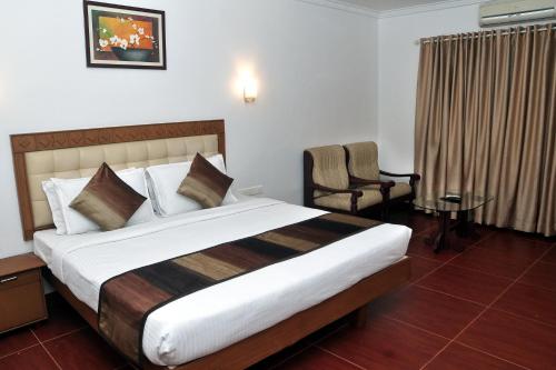 una habitación de hotel con una cama grande y una silla en BROAD BEAN Chakkarakkal en Chakkarakkal