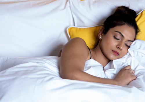 a woman laying in bed with her head on a pillow at Bloom Hotel - Brookefield in Bengaluru