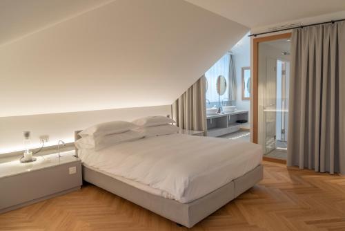 a white bedroom with a bed and a bathroom at CASPAR Swiss Quality Hotel in Muri