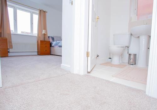 a white bathroom with a toilet and a window at Intellect Suites in Northampton