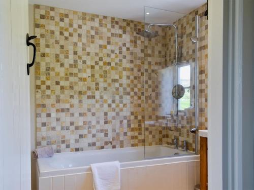 a bathroom with a tub and a glass shower at Periwinkle Cottage in Great Longstone