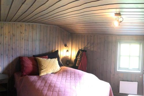 um quarto com uma cama rosa e um tecto de madeira em Seterhytte i Havsdalen em Geilo