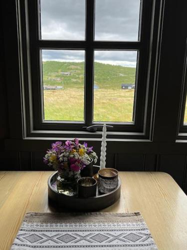 a table with flowers on it in front of a window at Seterhytte i Havsdalen in Geilo