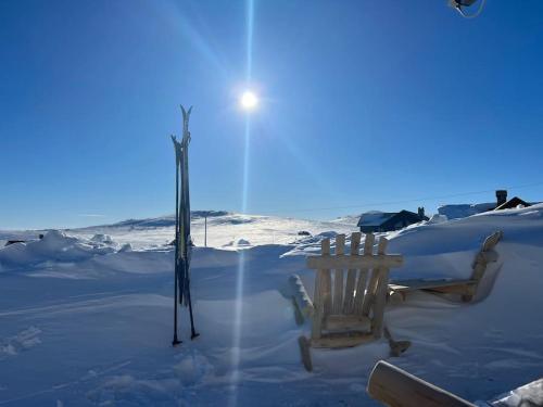 a bench and skis in the snow with the sun at Seterhytte i Havsdalen in Geilo