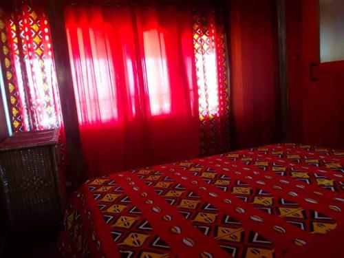 a red room with a bed with red curtains at CASE de ROBINSON in Lomé