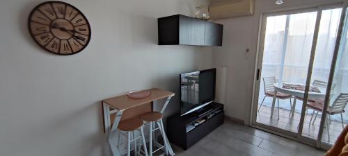 un salon avec une horloge au mur et une télévision dans l'établissement Appartement cosy en bord de mer, à Six-Fours-les-Plages