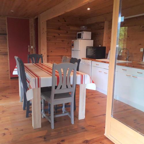 une cuisine et une salle à manger avec une table et des chaises dans l'établissement la cabane au fond du jardin, à Arsac