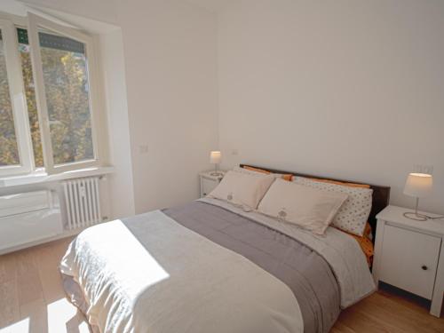 a white bedroom with a large bed with two windows at Olimpico deluxe apartment in Rome