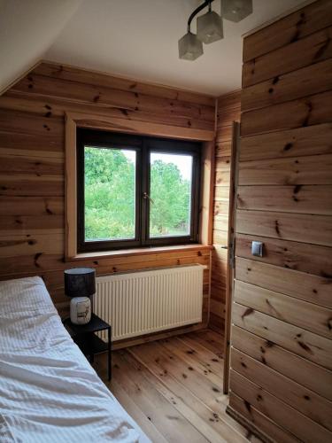 a bedroom with wooden walls and a bed and a window at Pod Żywotnikami in Białowieża