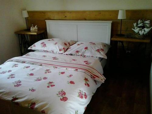 a bed with a white comforter with pink flowers on it at Chalupa U kapličky 