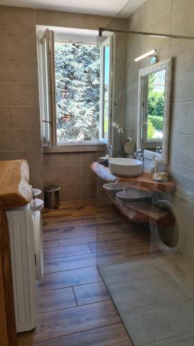 a bathroom with a sink and a mirror and a window at Dragonfly Appartamento Blu in Angera