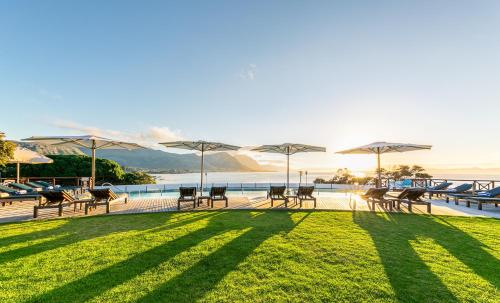 a patio area with chairs, tables and umbrellas at Harbour House Hotel in Hermanus