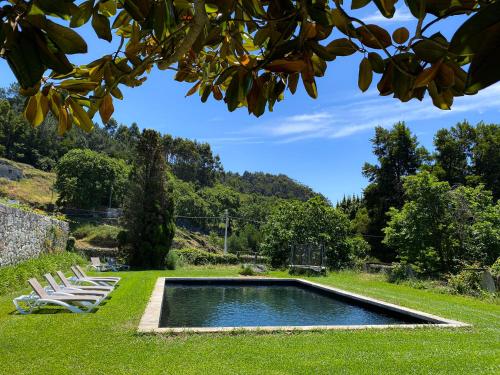 a swimming pool in the middle of a lawn with chairs at Quinta da Boa Viagem in Viana do Castelo