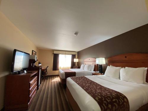 a hotel room with two beds and a flat screen tv at Best Western Manhattan Inn in Manhattan