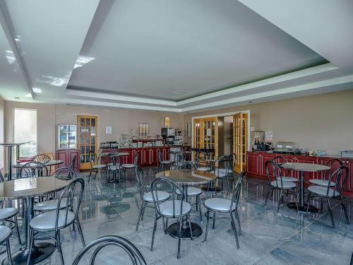 a dining room with tables and chairs and a kitchen at Quality Suites in Sainte-Anne-de-Beaupré