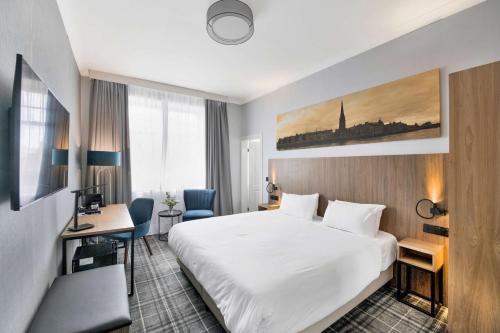 um quarto de hotel com uma cama branca e uma secretária em Radisson Blu Hotel, Perth em Perth