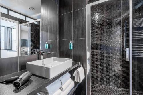 une salle de bain avec un lavabo et une douche dans l'établissement Yuna Les Halles - Serviced Apartments, à Paris