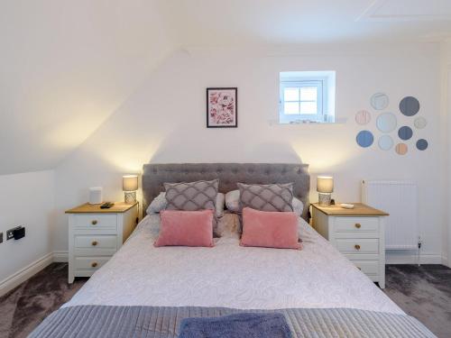 a bedroom with a large bed with pink pillows at Honey Bee House in Woodhall Spa