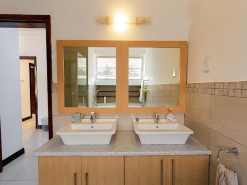 łazienka z 2 umywalkami i lustrem w obiekcie Unit 5, Capella Place w Akrze