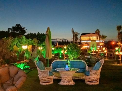 a patio with wicker chairs and a table and umbrella at White Country Boutique Hotel in Antalya