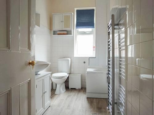 a white bathroom with a toilet and a sink at Oakleigh By The Sea in Cromer