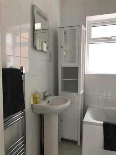 a white bathroom with a sink and a mirror at Fully Detached Studio Annexe with Double Bed for 2 & Sofa Bed for 2 in Cambourne