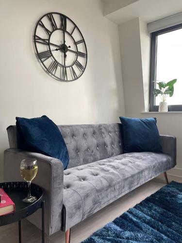 a living room with a couch and a clock on the wall at Premier Suite- Bedford city centre with free gym & parking in Bedford