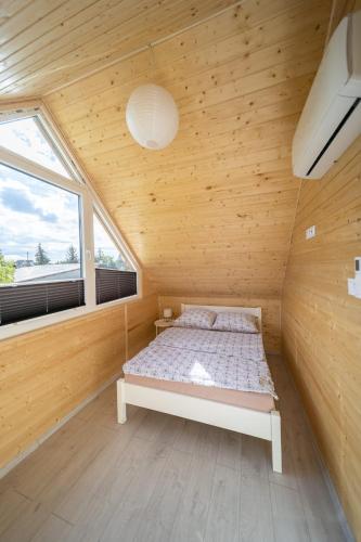 a bed in a wooden room with a window at Domki Kunice in Kunice
