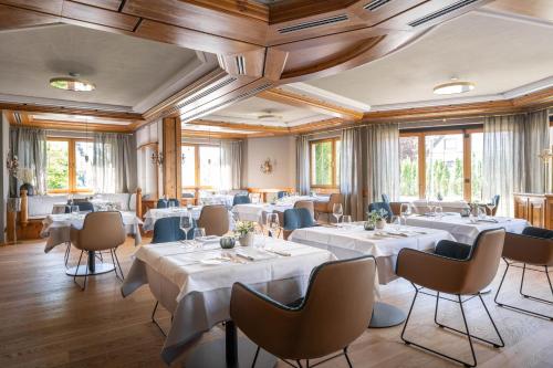 un restaurante con mesas y sillas blancas y ventanas en Hotel Maier en Friedrichshafen